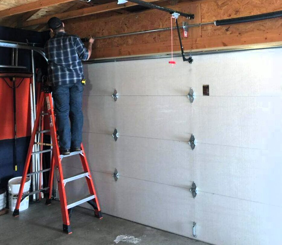 a professional technician repairing a garage door using specialized tools, representing the reliable garage door repair services offered by Foxleigh LLC